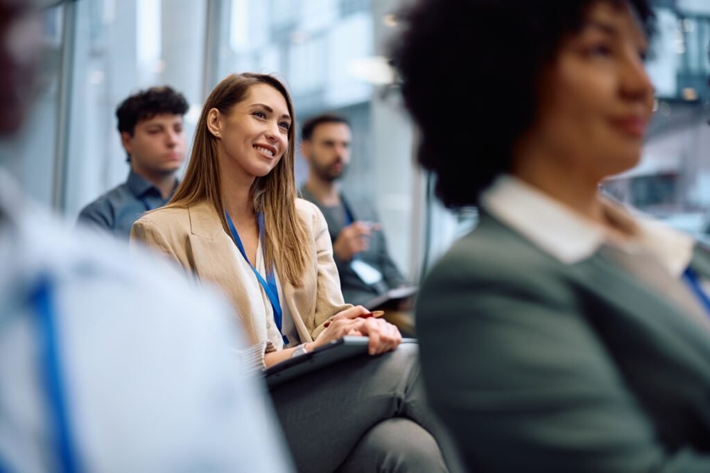 Young happy businesswoman participating in education event in a conference hall.